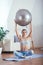 Young sportswoman doing exercises with ball on a mat at home