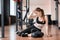 A young sportswoman sits on the floor near a kettlebell.