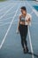 Young sportswoman with towel standing on running track stadium