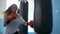 Young sportswoman wearing gloves in boxing hall beating a punching bag