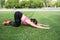 Young sportwoman stretching muscles over green background with copy space. Sunny day health lifestyle