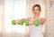 Young sporty attractive woman closeup portrait practicing fitness, holds green dumbbells, working out wearing sportswear, home int