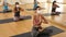 Young sporty brunette in protective face mask sitting on mat in lotus positions during group yoga training. Precautions