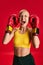 Young sporty emotional woman in sport wear and boxing gloves shouting loudly and closed eyes and ears of her self noise