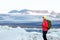 Young sporty girl with backpack admires beautiful view of the ice lake and mountains. Ice lagoon in Iceland