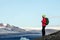 Young sporty girl with backpack admires beautiful view of the ice lake and mountains. Ice lagoon in Iceland