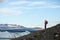 Young sporty girl with backpack admires beautiful view of the ice lake and mountains. Ice lagoon in Iceland