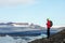 Young sporty girl with backpack admires beautiful view of the ice lake and mountains. Ice lagoon in Iceland