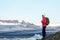 Young sporty girl with backpack admires beautiful view of the ice lake and mountains. Ice lagoon in Iceland