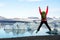 Young sporty girl with backpack admires beautiful view of the ice lake and mountains. Ice lagoon in Iceland