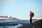 Young sporty girl with backpack admires beautiful view of the ice lake and mountains. Ice lagoon in Iceland