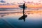 Young and sporty girl go to surfing. Beautiful woman in wetsuit and sunset on ocean