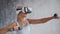 Young and sporty girl in sportswear is doing exercises at home using virtual reality helmet. Fit and slender blond woman