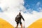 Young sporty guy with a backpack in a tent camp looking afar against a background of cumulus clouds and a blue sky.