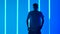 Young sporty man dancing hip hop against a background of bright blue neon lights. A silhouetted male dancer in casual