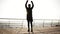 Young sporty man exercising on the dock near the seaside. Beautiful sunny morning on the seacoast. Outdoors footage.