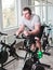 Young sporty man in white t-shirt and shorts is exercising bike at spinning class