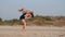 Young sporty mother with little daughter doing gymnastic on the beach.