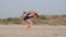 Young sporty mother with little daughter doing gymnastic on the beach.