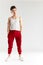 Young sporty stylish male dancer in red sweatpants posing isolated in studio