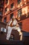 Young sporty teenager girl on roof of high-rise apartment building on brick wall background