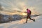 Young sporty woman downhill in the snow with snowshoes in a sunset landscape