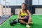 Young sporty woman drinking water in gym, holding bottle, having break