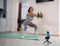 Young sporty woman performing dumbbell squats with elastic fitness band while watching workout tutorials