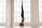Young sporty woman practicing yoga, doing headstand exercise