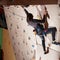 Young sporty woman reaching the top of artificial bouldering wall while exercising in bouldering gym indoors