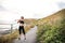 Young sporty woman runner in black activewear standing outside in nature, stretching.