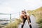 Young sporty woman runner in black activewear standing outside by the seaside, resting.