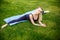 Young sporty woman sitting on grass in the park,gymnastic splits.