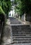 Young sporty woman in sportswear running up steep cobblestone stairs in green alley