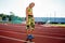 Young sporty woman sprinter athlete in sportswear resting after run on stadium track