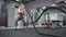 Young sporty woman working out with Fitness battling ropes at gym
