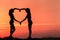 Young sporty women holding hands in heart shape at sunset