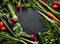 Young spring vegetables on black chalkboard from above