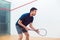 Young squash player holding the racket during game on a professional court