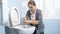 Young squeamish housewife cleaning dirty toilet with brush