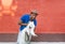 Young Sri Lankan and his fluffy white dog against the background of a red brick wall.