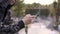 Young streetstyle man in hoodie using his smartphone in hood, Sitting on the fence of skatepark