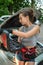 young strong with a good figure brunette woman repairs a car with an open hood on the road
