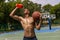 Young strong man, male basketball player training at street public stadium, sport court or palyground outdoors. Concept