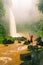 Young strong man traveler enjoy spectacular morning view, beautiful Nungnung Waterfall, Indonesia