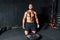 Young strong muscular man with big muscles sitting on the gym floor after heavy workout training with barbell weight plate