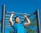 Young strong sportive man swinging on monkey bars during street workout