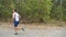 Young strong sportsman with wireless headphones jogging along trail near forest. Sporty man running along road at nature