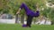 Young strong sporty woman in hijab and purple pants top practicing outdoors, girl trainer doing supported headstand