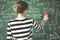 Young student cleaning green chalkboard with duster in classroom